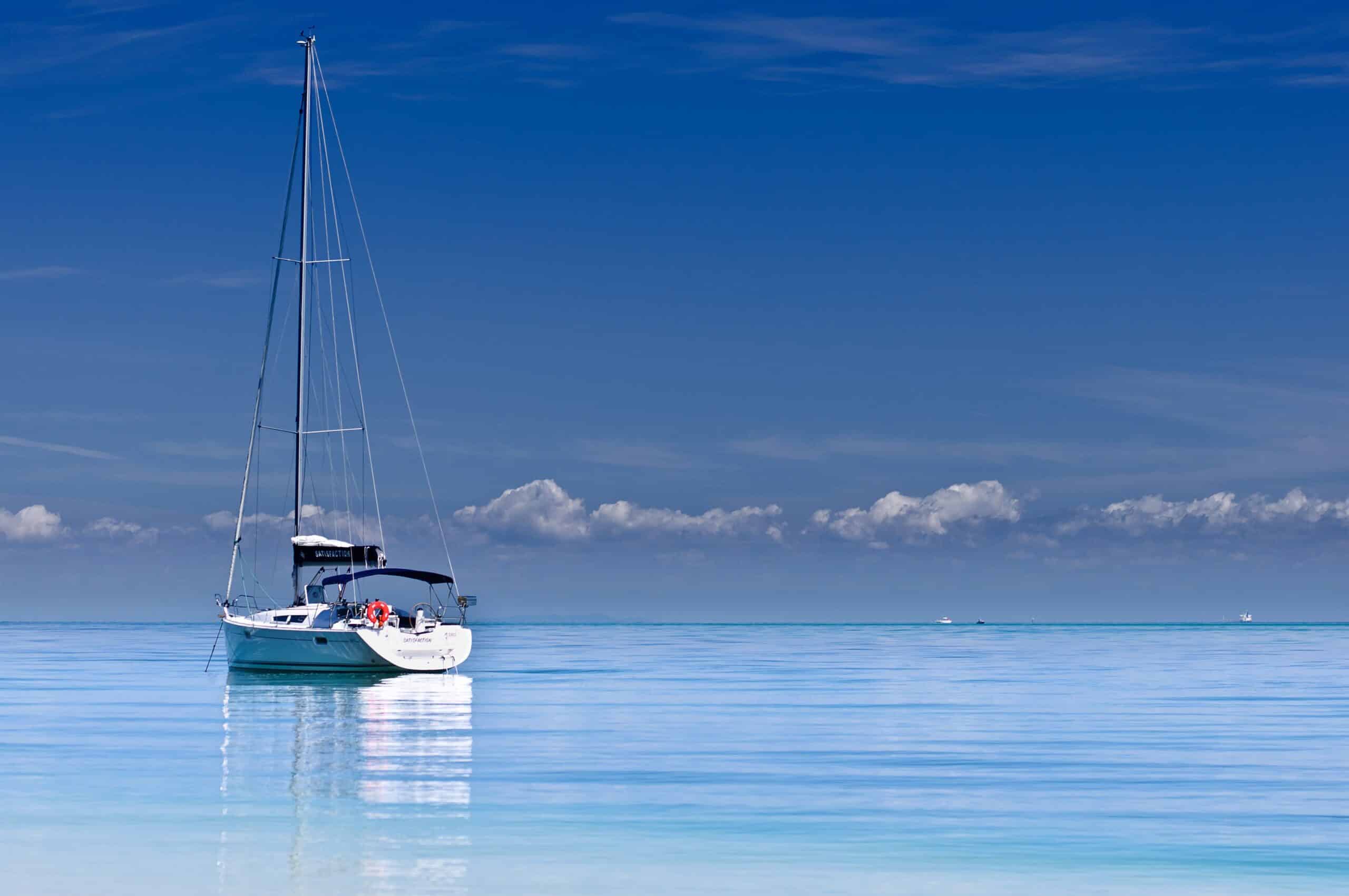 Ein weißes Segelboot, das im klaren blauen Wasser schwimmt.